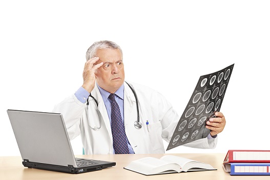Shocked doctor looking at an x-ray seated at a table